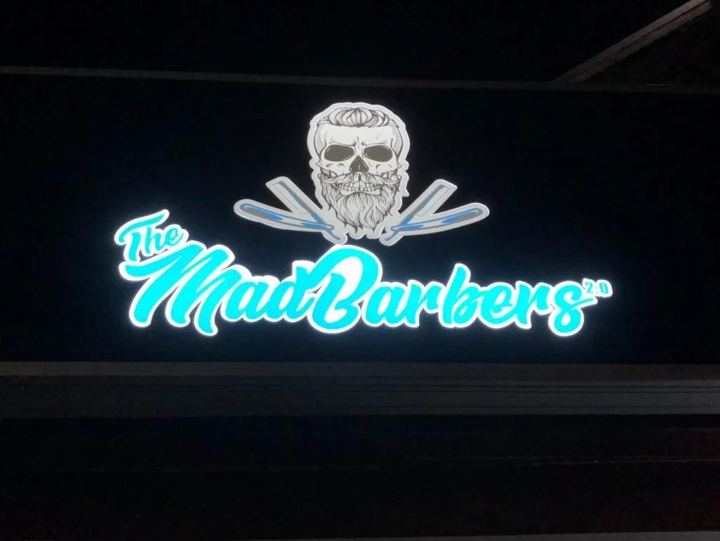 The Mad Barbers light sign with skull and razors at night