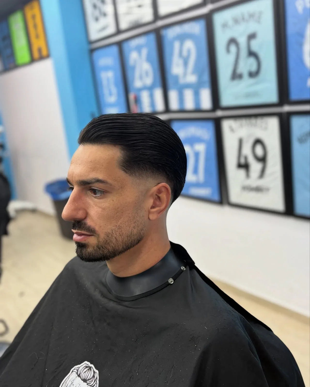 Slicked back hair with a sharp fade and beard line